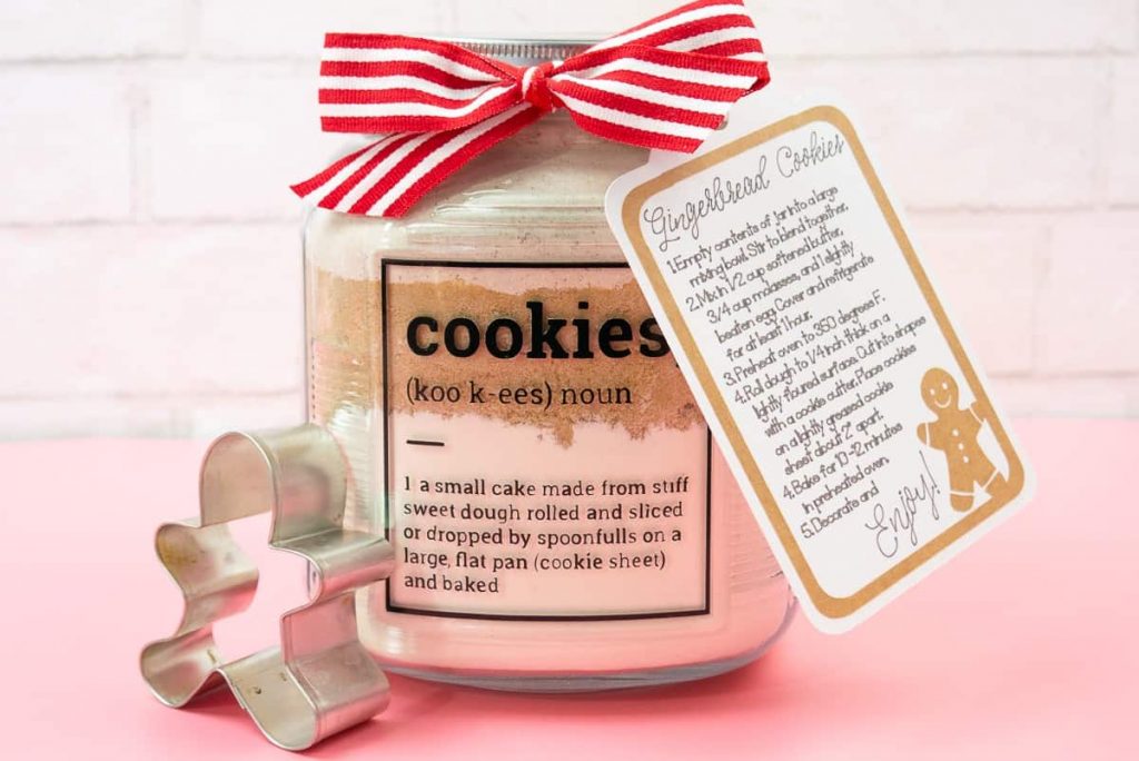 Gingerbread Cookies In a Jar Holiday Gift on a pink background with cookie cutter.